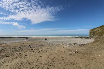 a beach with people walking on the sand at Hay Loft in Camborne