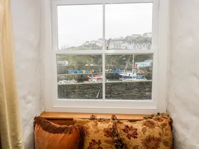a couch in front of a window with a view of a harbor at Glanville House in Mevagissey