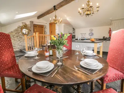 a dining room with a wooden table and red chairs at Glanville House in Mevagissey