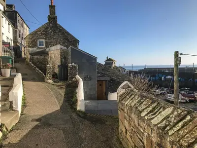 an old stone house with a stone wall and a street at Glanville House in Mevagissey