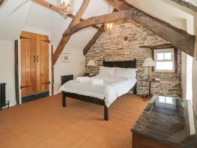 a bedroom with a bed and a stone wall at Glanville House in Mevagissey