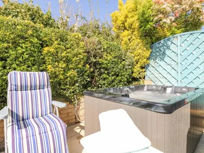 a chair and a hot tub on a patio at Respryn in Mevagissey