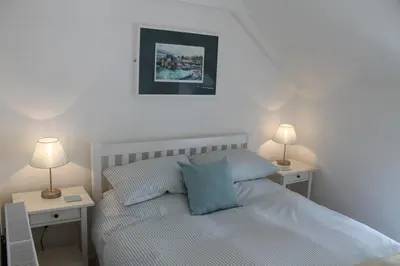a bedroom with a bed with two night stands and two lamps at Hillside Cottage in Wadebridge
