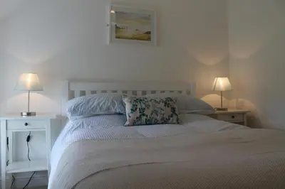 a bedroom with a white bed with two lamps at Hillside Cottage in Wadebridge