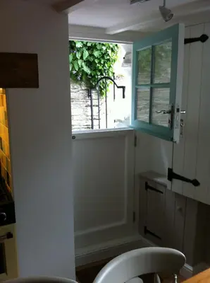a kitchen with a window and a table and a chair at Hillside Cottage in Wadebridge