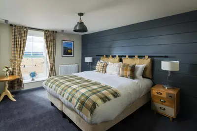 a bedroom with a large bed with a blue wall at Lifeboat Inn in St Ives