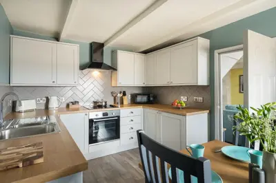 a kitchen with white cabinets and a wooden table at Lifeboat Inn in St Ives