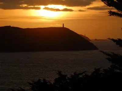 a sunset over a hill with a lighthouse on it at Bishops View in Polzeath