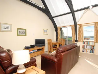 a living room with a leather couch and a television at Bishops View in Polzeath