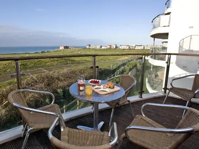 a table and chairs on a balcony with a view of the ocean at Fistral View At Bredon Court in Newquay