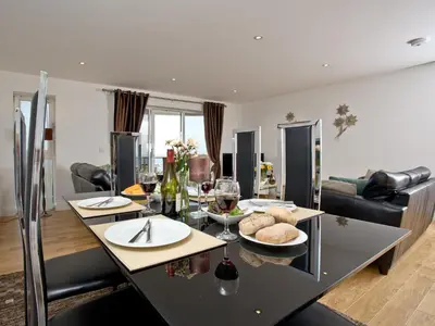 a kitchen and living room with a table with glasses of wine at Fistral View At Bredon Court in Newquay