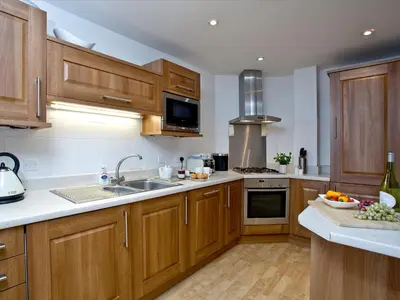a kitchen with wooden cabinets and a sink at Fistral View At Bredon Court in Newquay
