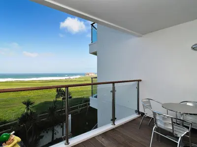 a balcony with a table and chairs and a view of the ocean at 28 Bredon Court in Newquay