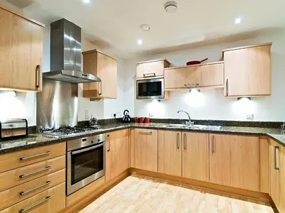 a kitchen with wooden cabinets and a stove top oven at 28 Bredon Court in Newquay