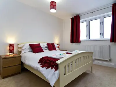 a bedroom with a white bed and red curtains at 28 Bredon Court in Newquay