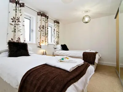 two beds in a room with white walls and windows at 28 Bredon Court in Newquay