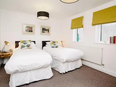 two beds in a room with white walls and windows at 50 Bredon Court in Newquay