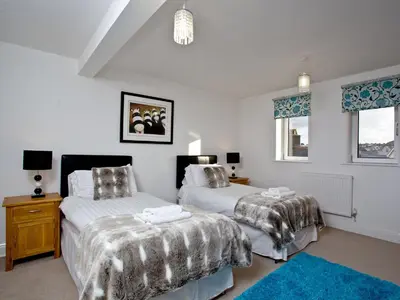 a bedroom with two beds and a blue rug at Bredon Court, Poseidon Penthouse in Newquay