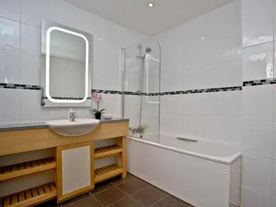 a bathroom with a sink and a tub and a mirror at Bredon Court, Poseidon Penthouse in Newquay