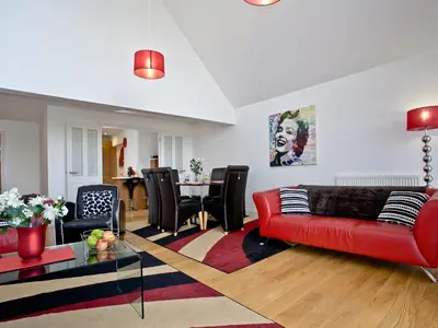 a living room with a red couch and a table at Bredon Court, Poseidon Penthouse in Newquay