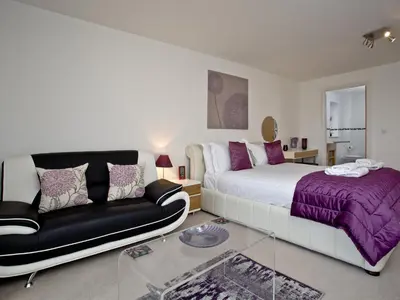 a bedroom with a bed and a couch at Bredon Court, Poseidon Penthouse in Newquay