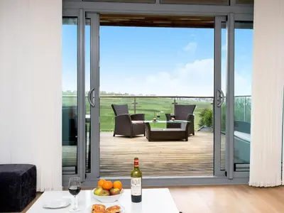 a living room with a sliding glass door to a patio at Fistral View - 3 Cribbar in Newquay