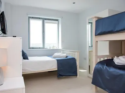 a bedroom with two beds and two windows at Fistral View - 3 Cribbar in Newquay