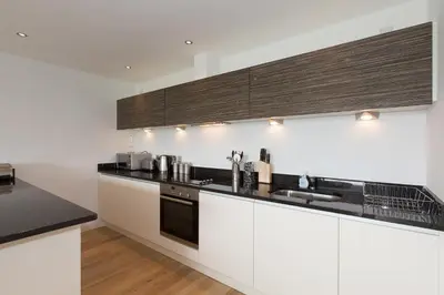 a kitchen with white cabinets and black counter tops at Fistral View - 3 Cribbar in Newquay