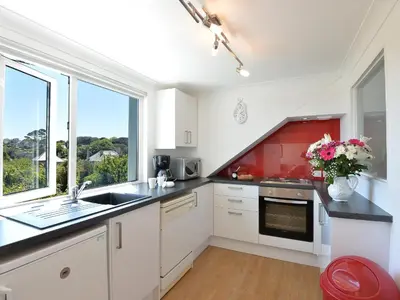 a kitchen with white cabinets and a sink and a window at Florizel in Falmouth