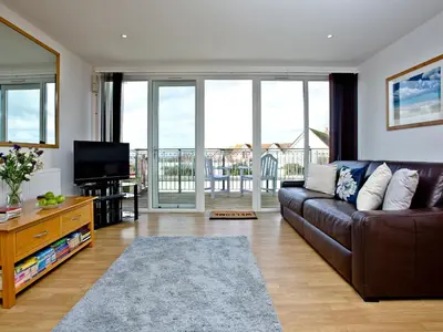 a living room with a brown couch and a television at Sea Glimpses in Saint Columb Minor