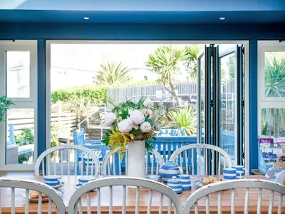 a table with chairs and a vase with flowers on it at Headland Views in Newquay