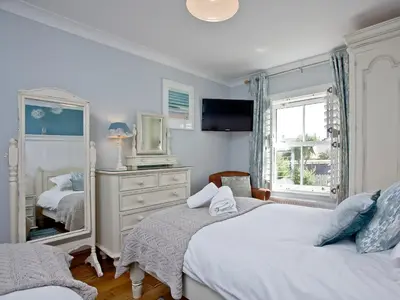 a bedroom with two beds and a dresser with a mirror at Headland Views in Newquay