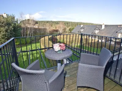 a balcony with chairs and a table with a vase of flowers at Holly in Saint Wenn