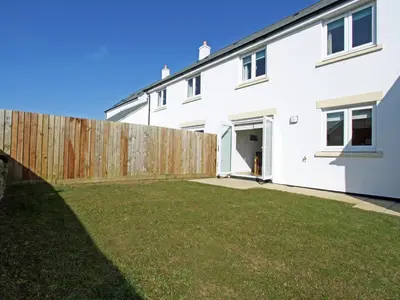 a white house with a wooden fence at 6 Jubilee Close in St Merryn