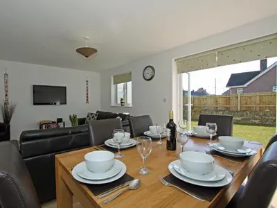 a dining room with a table with chairs and a couch at 6 Jubilee Close in St Merryn
