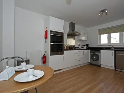 a kitchen with white cabinets and a wooden table at 6 Jubilee Close in St Merryn