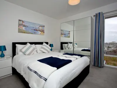 a bedroom with a large bed and a large window at Above Towan At 8 Quay Court in Newquay