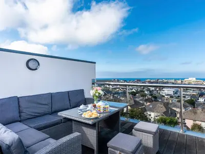 a patio with a couch and a table on a balcony at Above Towan At 8 Quay Court in Newquay