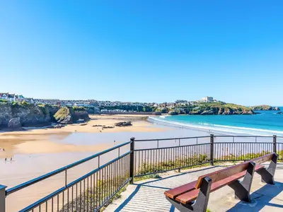 a wooden bench sitting on a boardwalk next to a beach at Above Towan At 8 Quay Court in Newquay