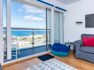 a living room with a couch and a large window at Above Towan At 8 Quay Court in Newquay