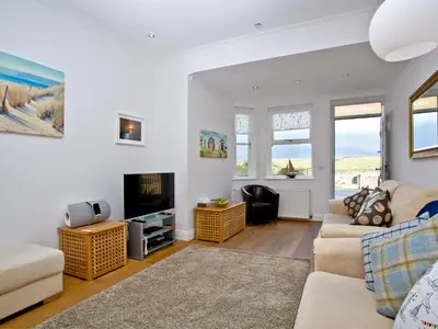 a living room with a couch and a tv at Quay House, Porth Beach in Newquay