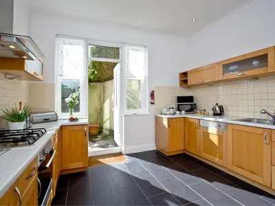 a large kitchen with wooden cabinets and a window at Quay House, Porth Beach in Newquay