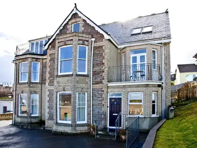 a brick house with a porch and a balcony at Quay House, Porth Beach in Newquay