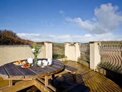 a wooden table with a bowl of fruit on a balcony at Quay House, Porth Beach in Newquay