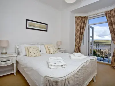 a bedroom with a white bed and a window at Quay House, Porth Beach in Newquay