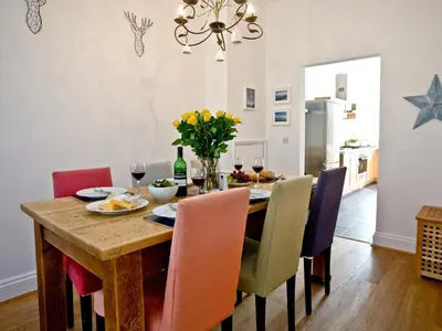 a dining room table with chairs and a vase of flowers at Quay House, Porth Beach in Newquay