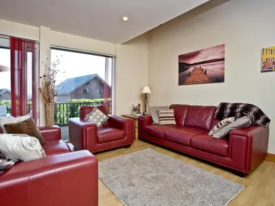 a living room with two red leather couches at Ash Lodge - Retallack in Saint Columb Major