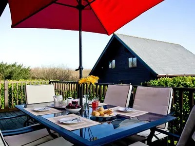 a table with a red umbrella on a patio at Ash Lodge - Retallack in Saint Columb Major