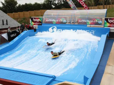 two people riding a wave in an indoor wave pool at Beech Lodge - Retallack Resort in Saint Columb Major