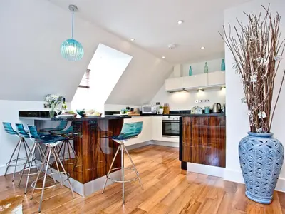 a kitchen with a bar with blue chairs and a vase at 9 The Whitehouse in Mawgan Porth